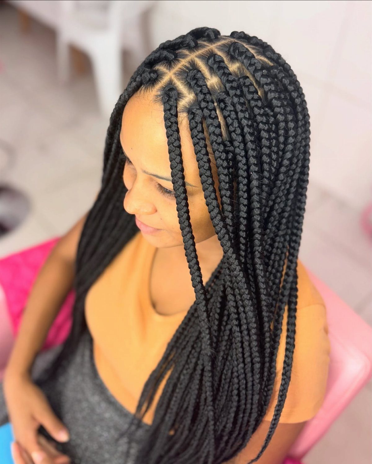 Woman with long black box braids and visible square scalp sections.