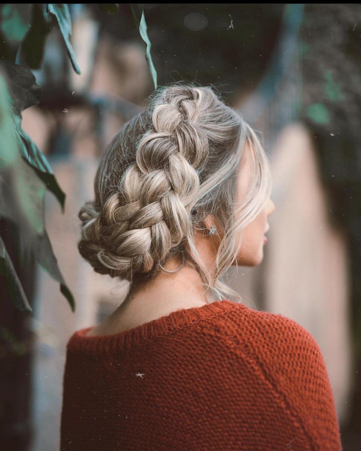 Blonde hair styled in a thick braid wrapping into a low bun.