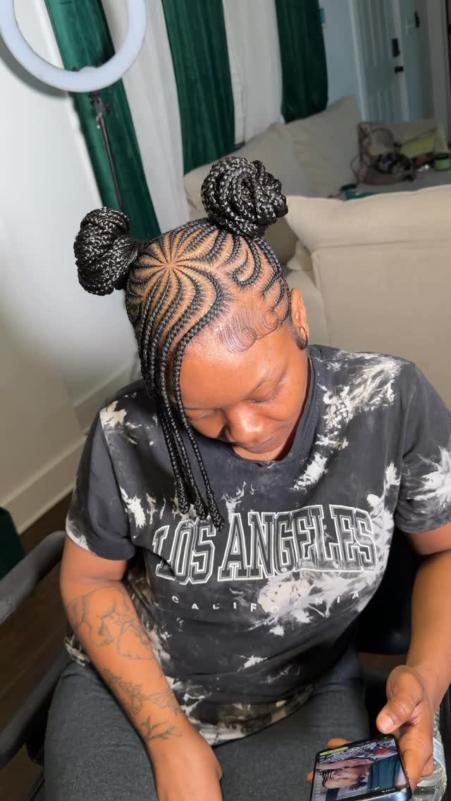 Woman with cornrows styled into two braided space buns on top of her head.