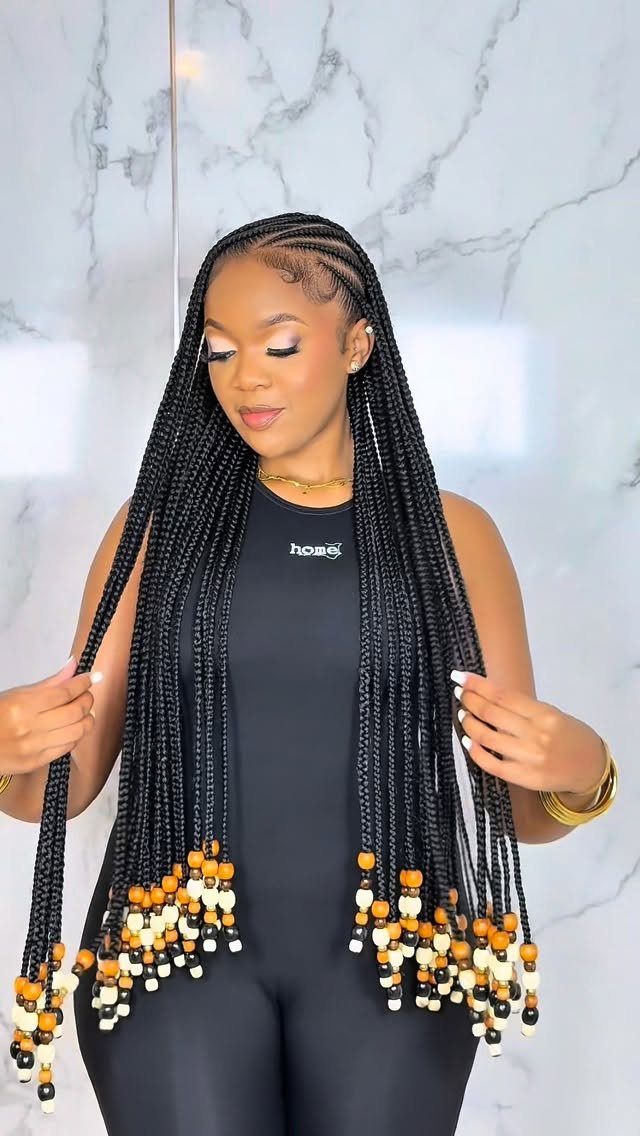 Woman with long black box braids featuring white and yellow beads at the ends.