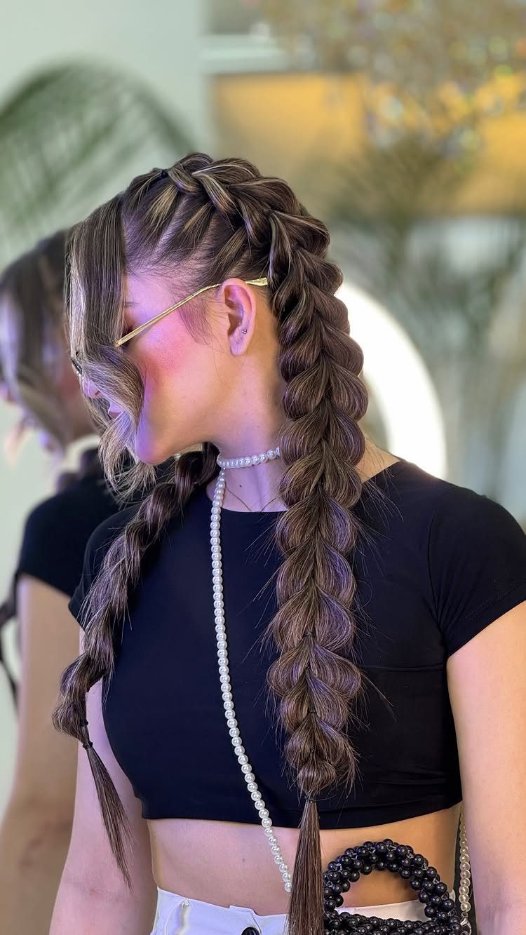 Woman with brown hair styled in two long, thick fishtail braids.