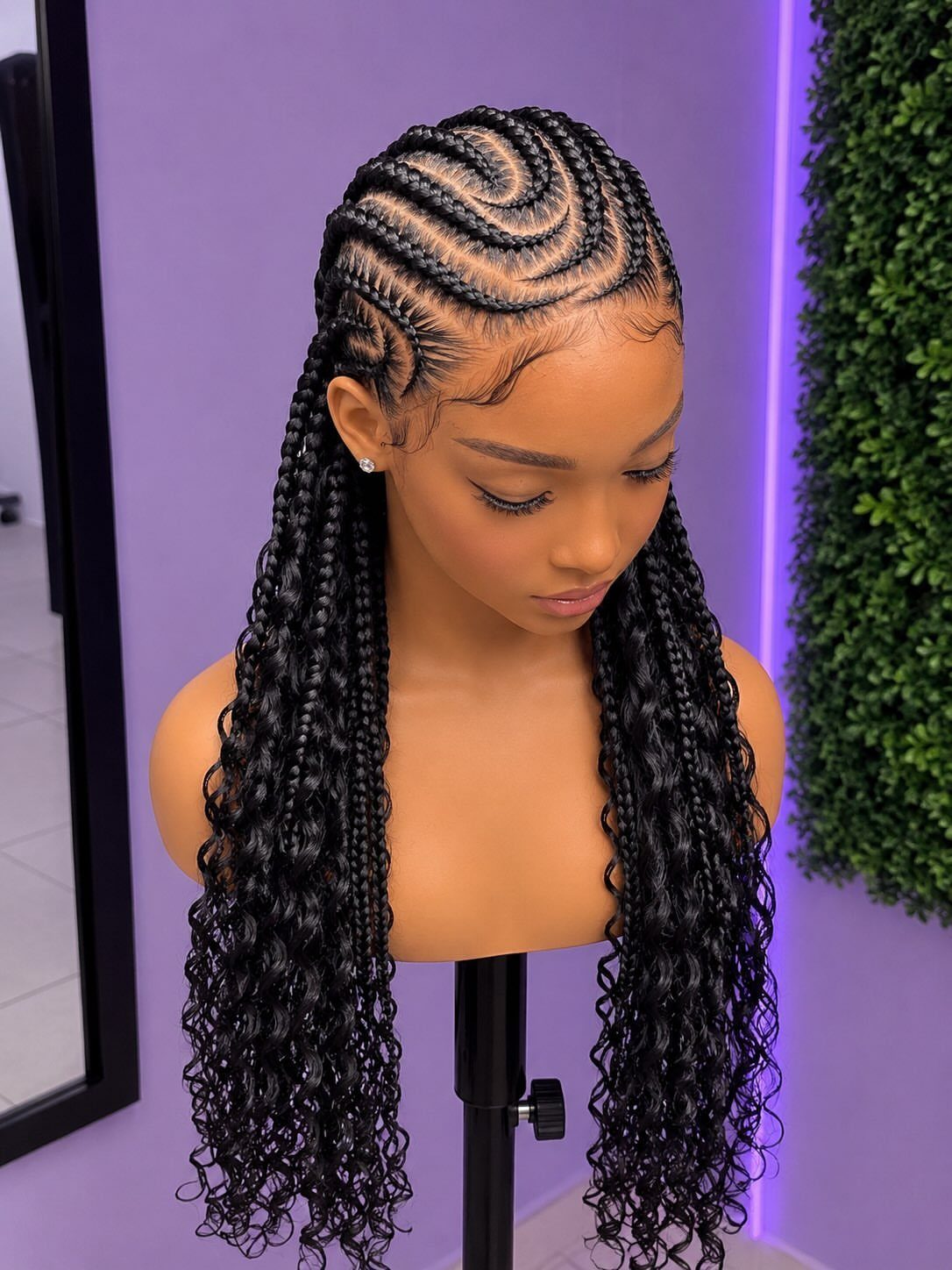 Mannequin head with curved cornrows and long black goddess braids with curly ends.