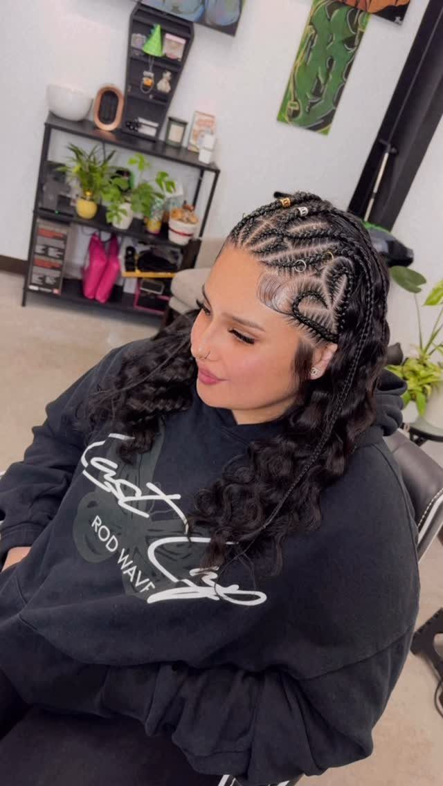 Woman with intricate cornrow braids on top and loose curly hair flowing down.