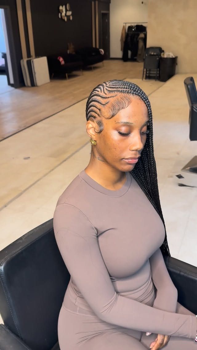Woman with long lemonade braids and a deep side part in a salon.
