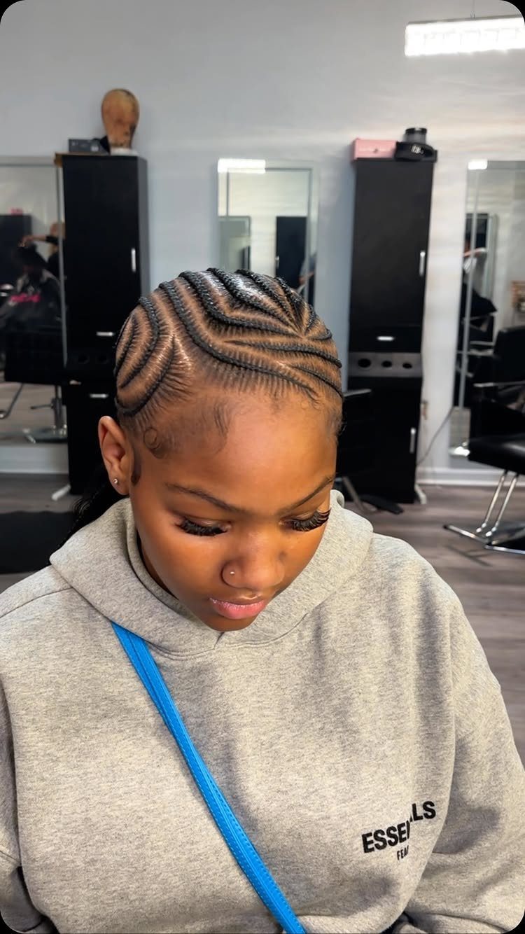 Woman with curved stitch braids styled across her scalp in a hair salon.