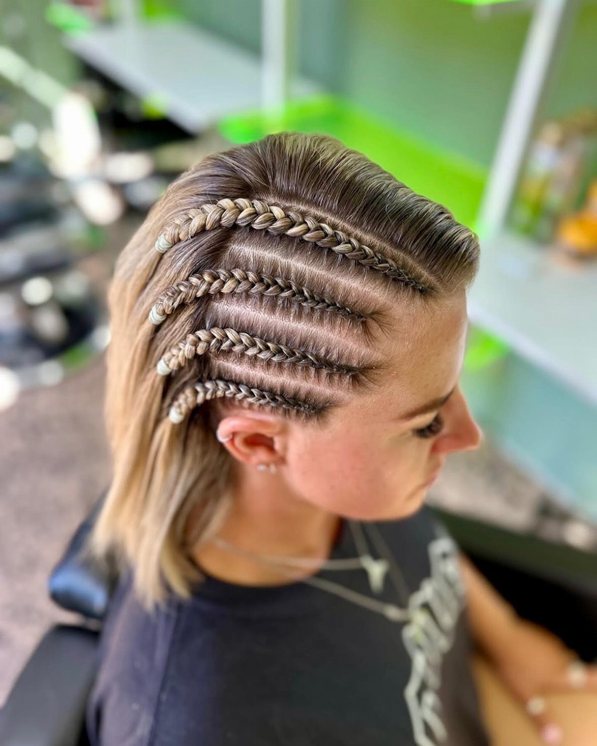 Woman with blonde hair styled in multiple thick side Dutch braids.