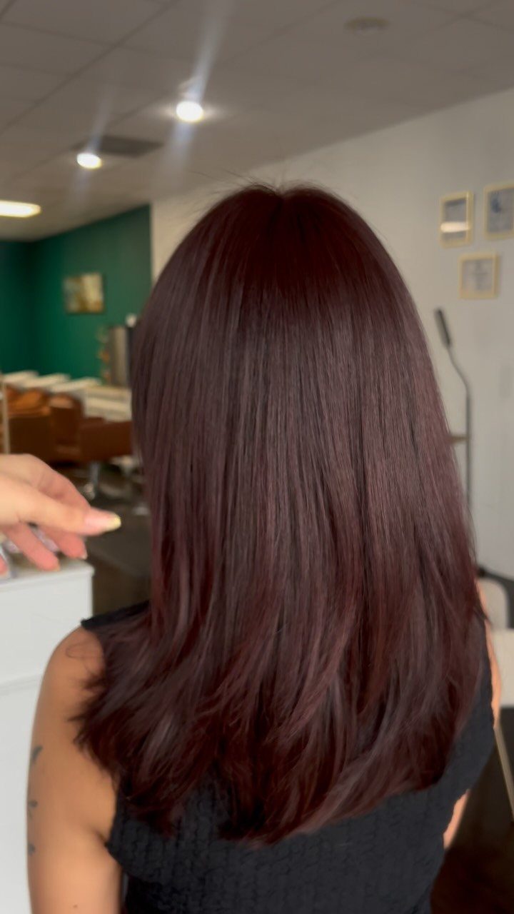 Shiny deep burgundy red hair showing a glossy finish in a salon setting