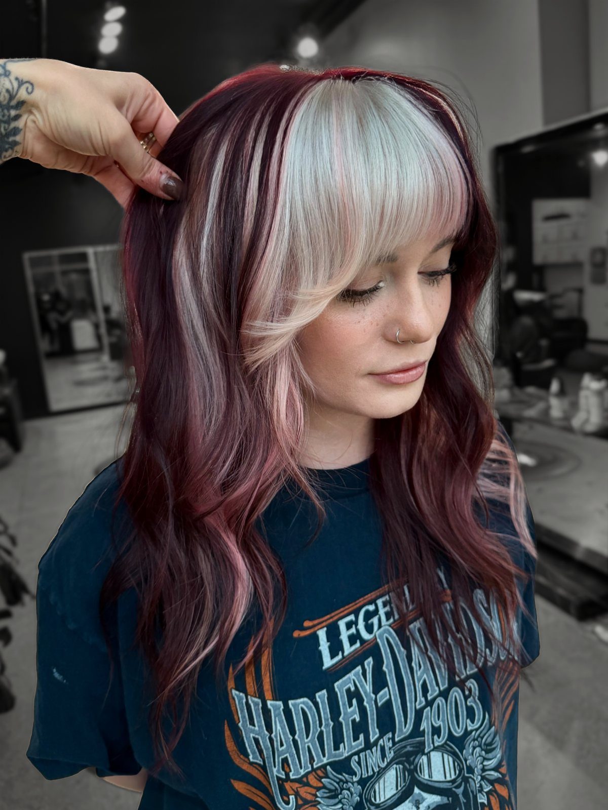 Woman with shiny burgundy and white hair showing off a glossy hair color result.
