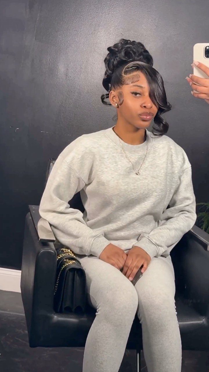 Woman with a high voluminous updo and side-swept bangs wearing grey loungewear.