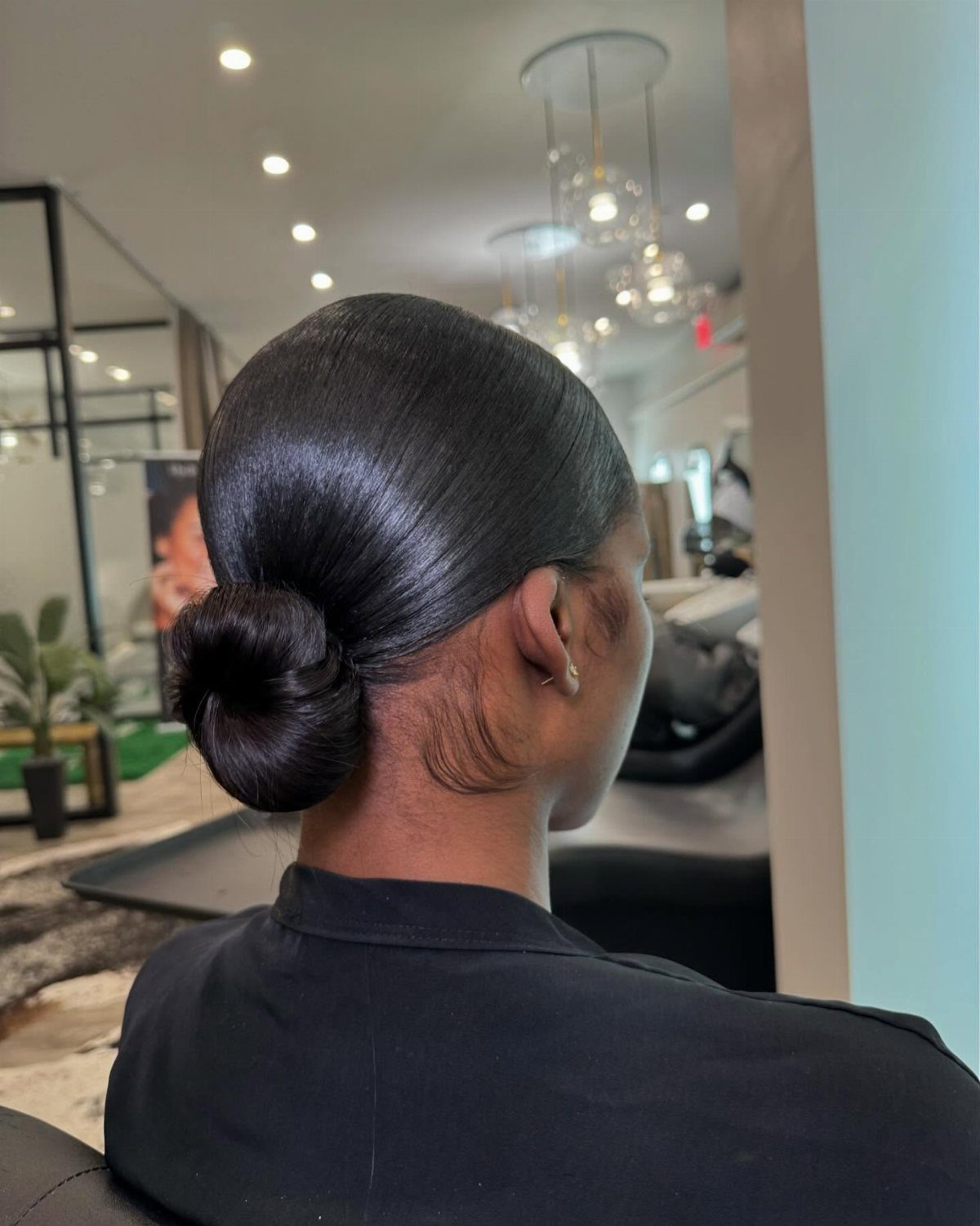 Sleek dark hair styled into a tight ballerina bun at the nape.