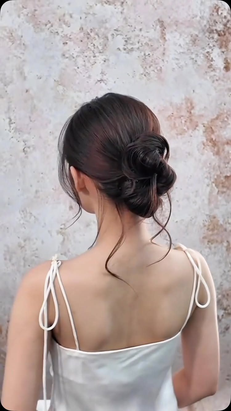 Woman with dark brown hair styled in a low twisted updo bun.