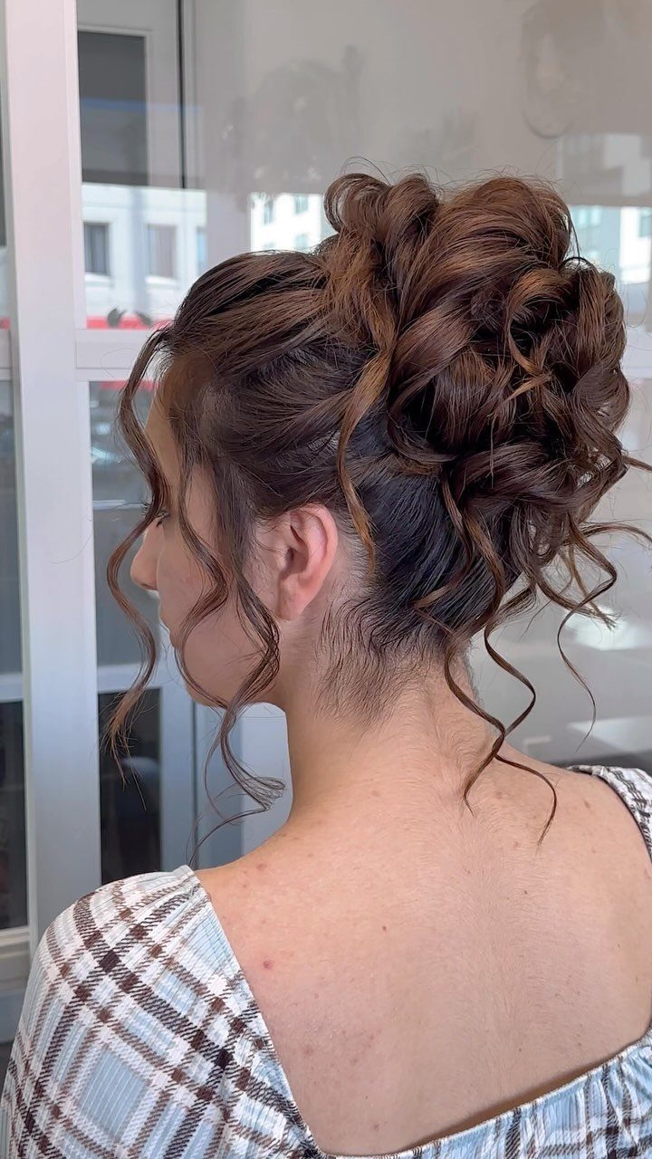 Woman with brown hair in a loose, curly updo with face-framing ringlets.