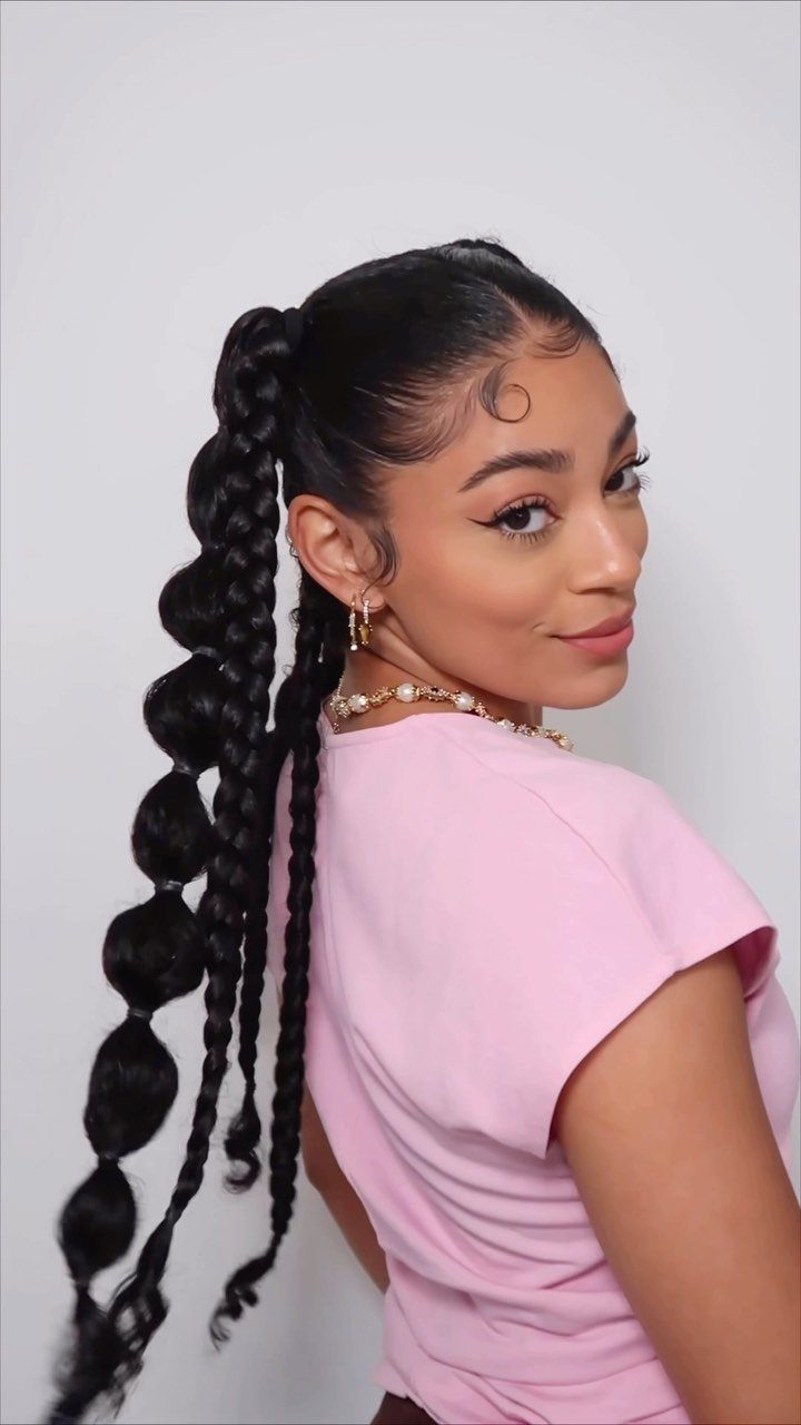 Woman with dark hair in a high ponytail featuring bubble braids and pink shirt.