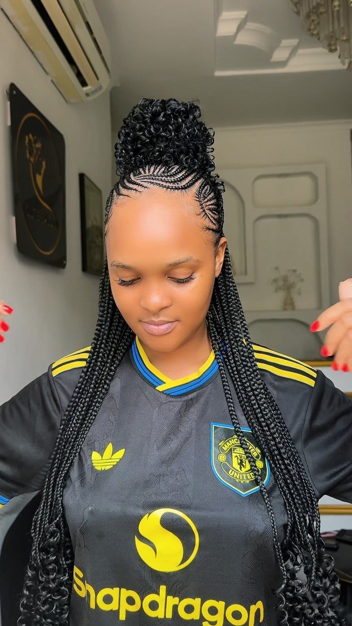 Woman with a high curly ponytail and long thin braids wearing a jersey.