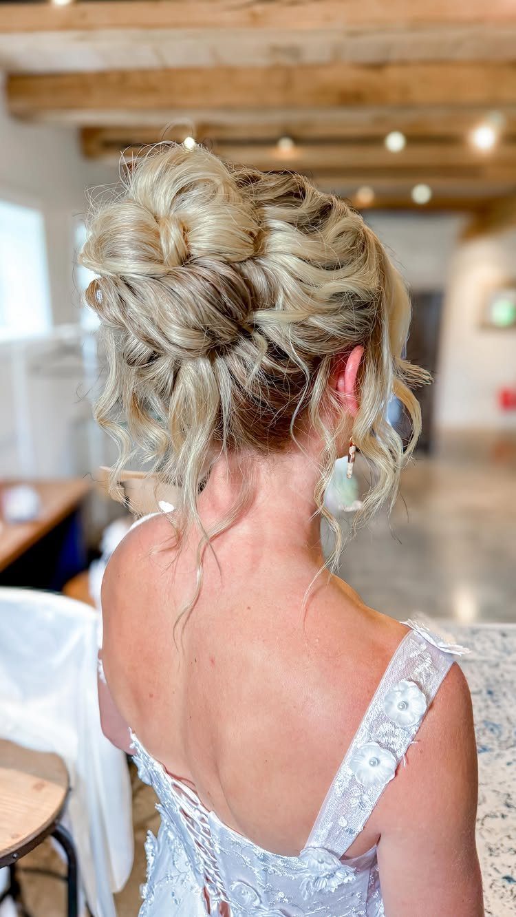 Blonde woman with a messy textured updo wearing a white lace-up dress