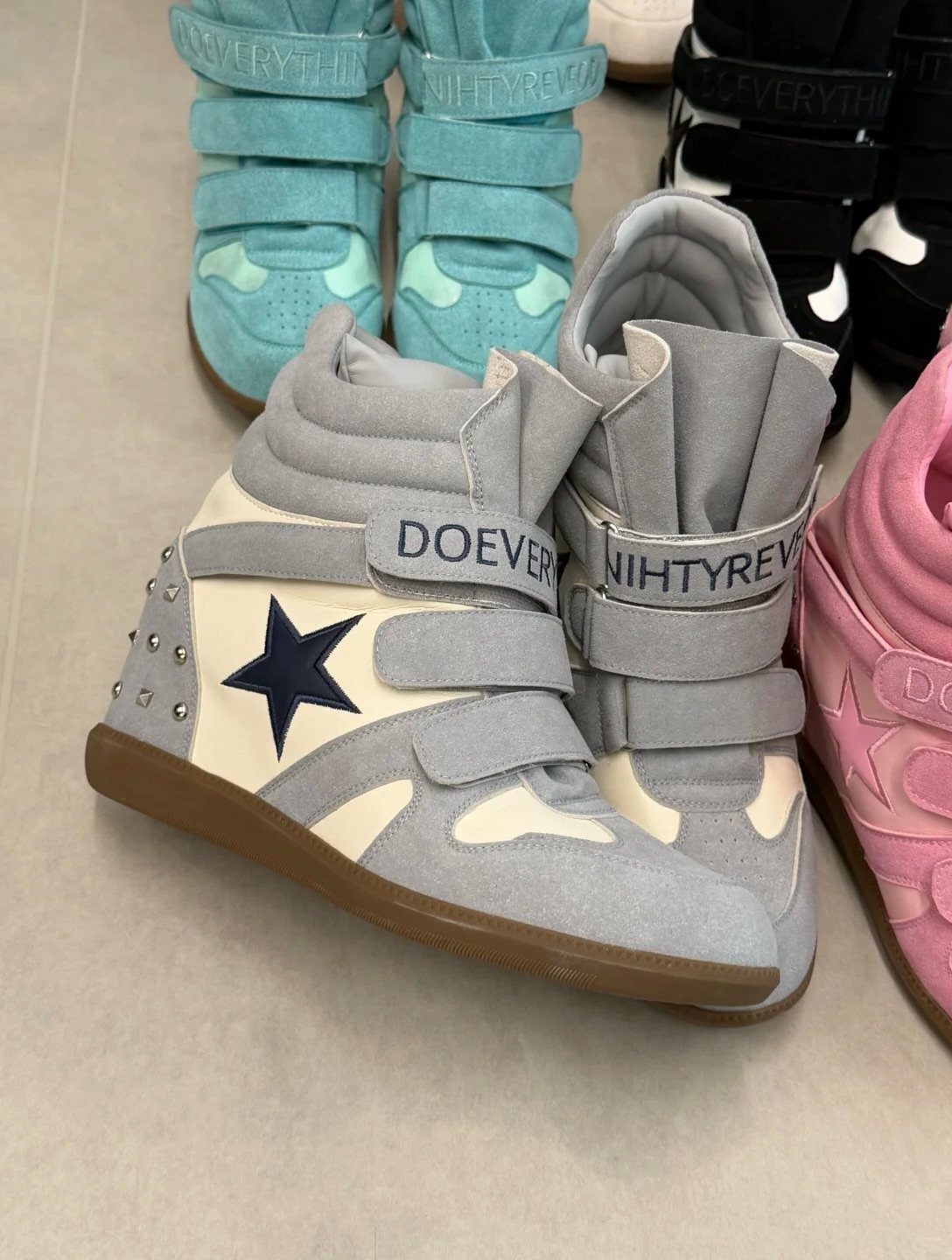 Grey high-top sneakers with a blue star and hidden wedge sole on floor