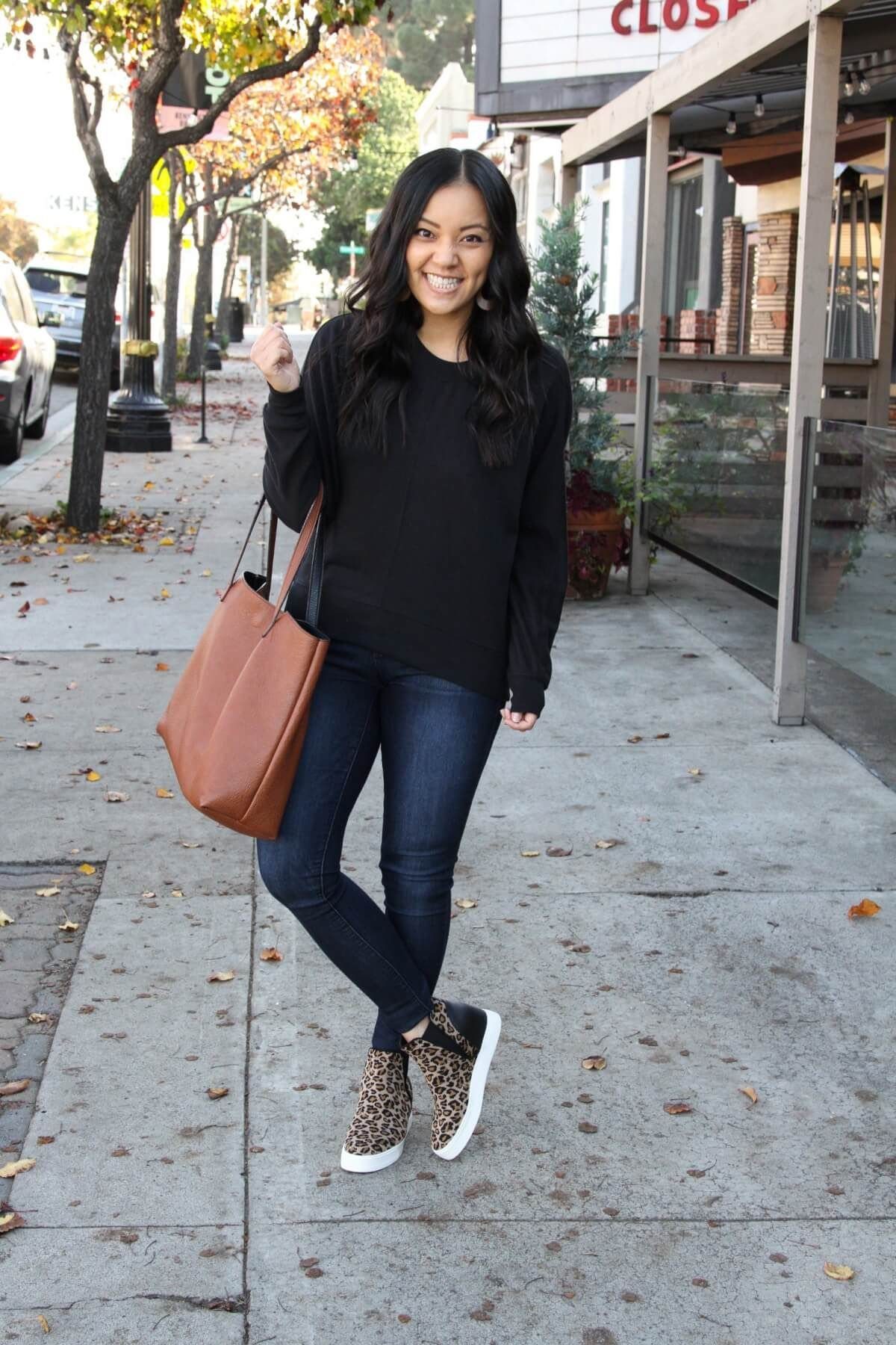 Woman wearing leopard print wedge sneakers paired with dark blue skinny jeans