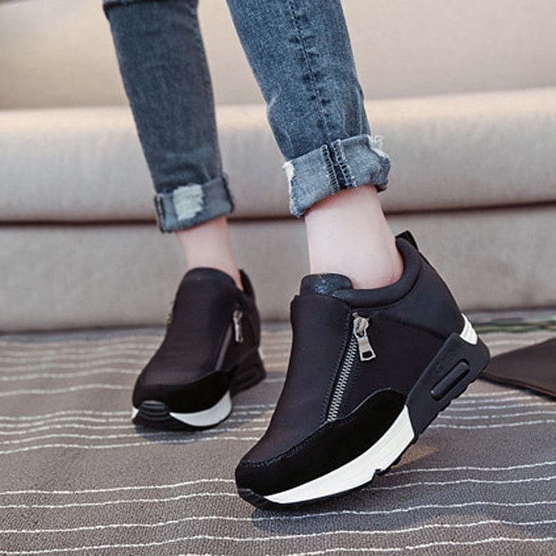 Black wedge sneakers with zippers worn with cuffed blue denim jeans