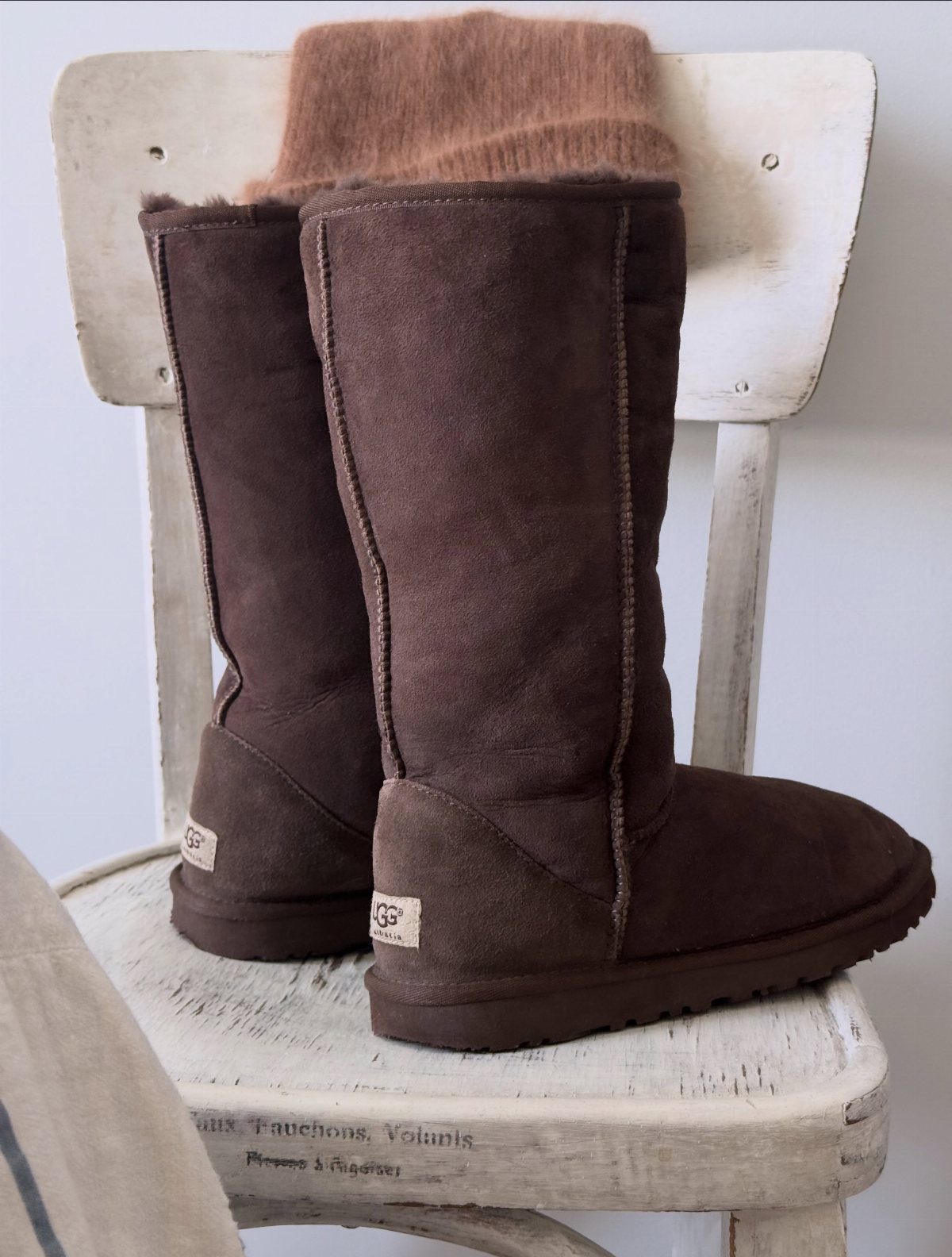 High UGG Boots: 6 Tall Styles From Classic to Adirondack 3 Tall dark brown suede boots resting on a rustic white wooden chair