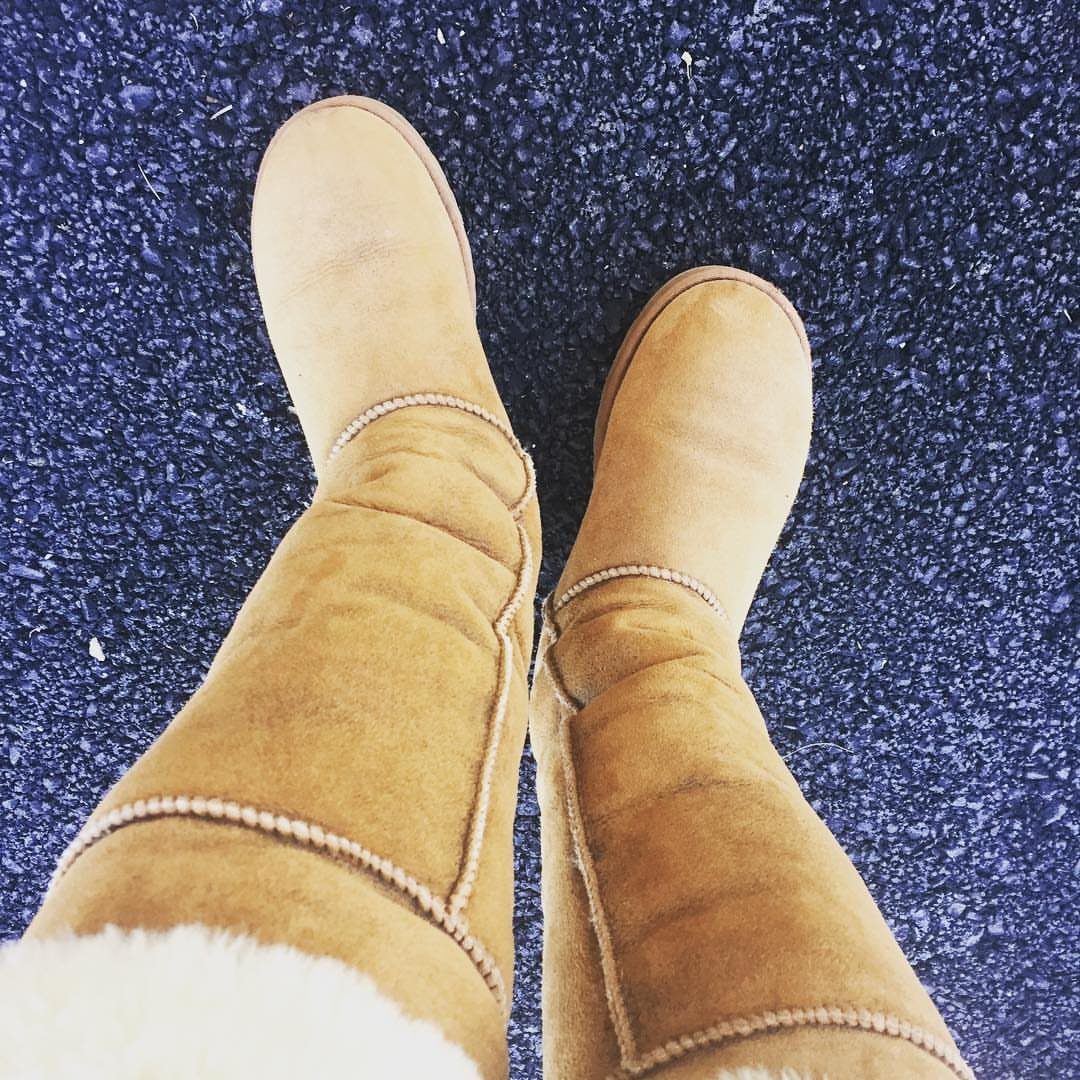 High UGG Boots: 6 Tall Styles From Classic to Adirondack 4 Tall tan suede boots with white faux-fur lining on blue asphalt ground.
