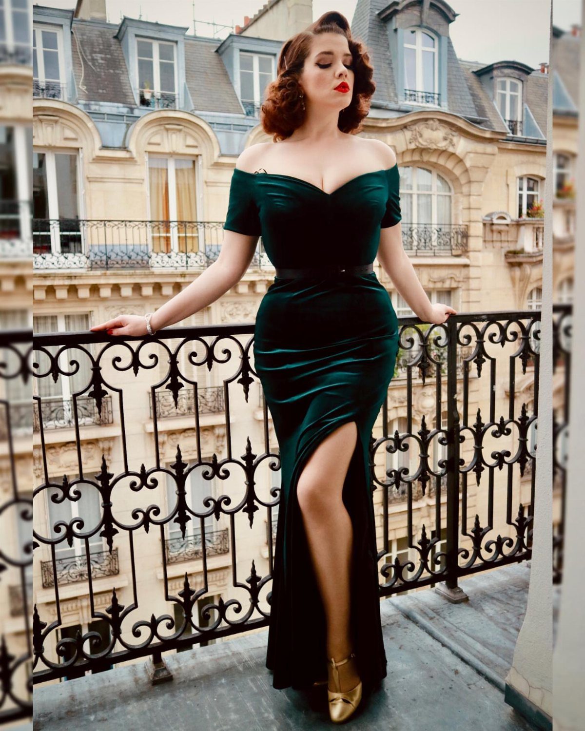 Woman in dark green velvet gown posing on a Parisian balcony with iron railing.