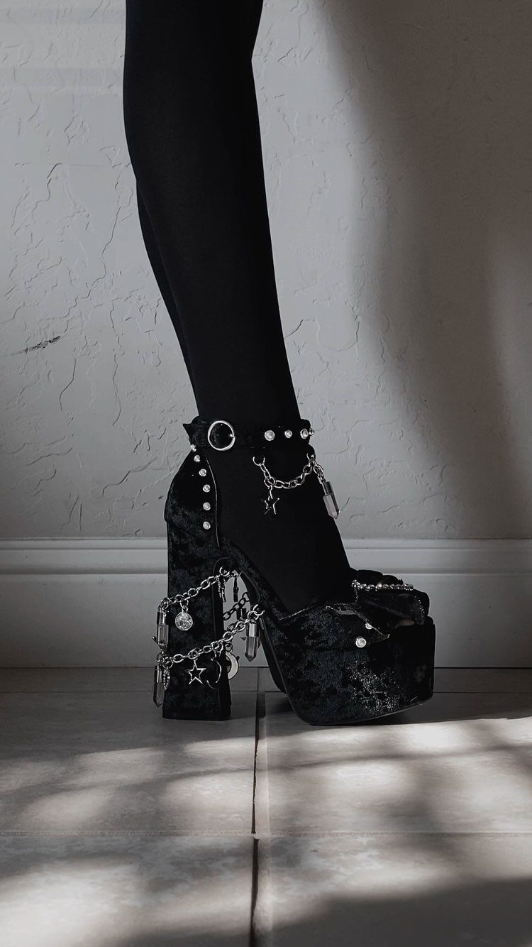 Black glitter platform heels with silver chains and charms worn with black tights.