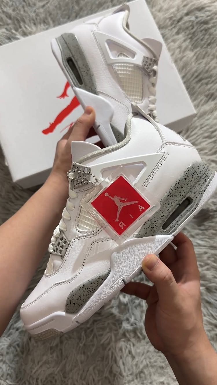 White and grey high-top Jordan sneakers held over a white branded shoe box.