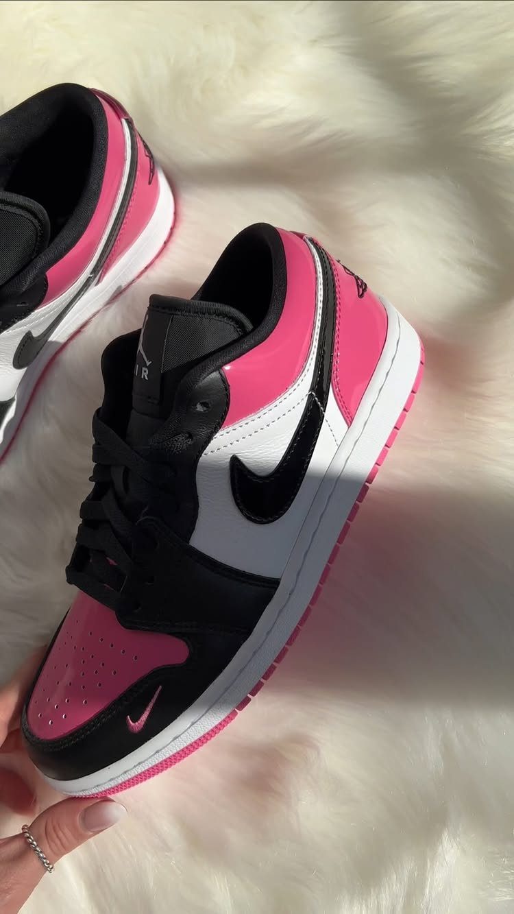 Pink, white, and black high-top sneakers resting on a white faux-fur rug.