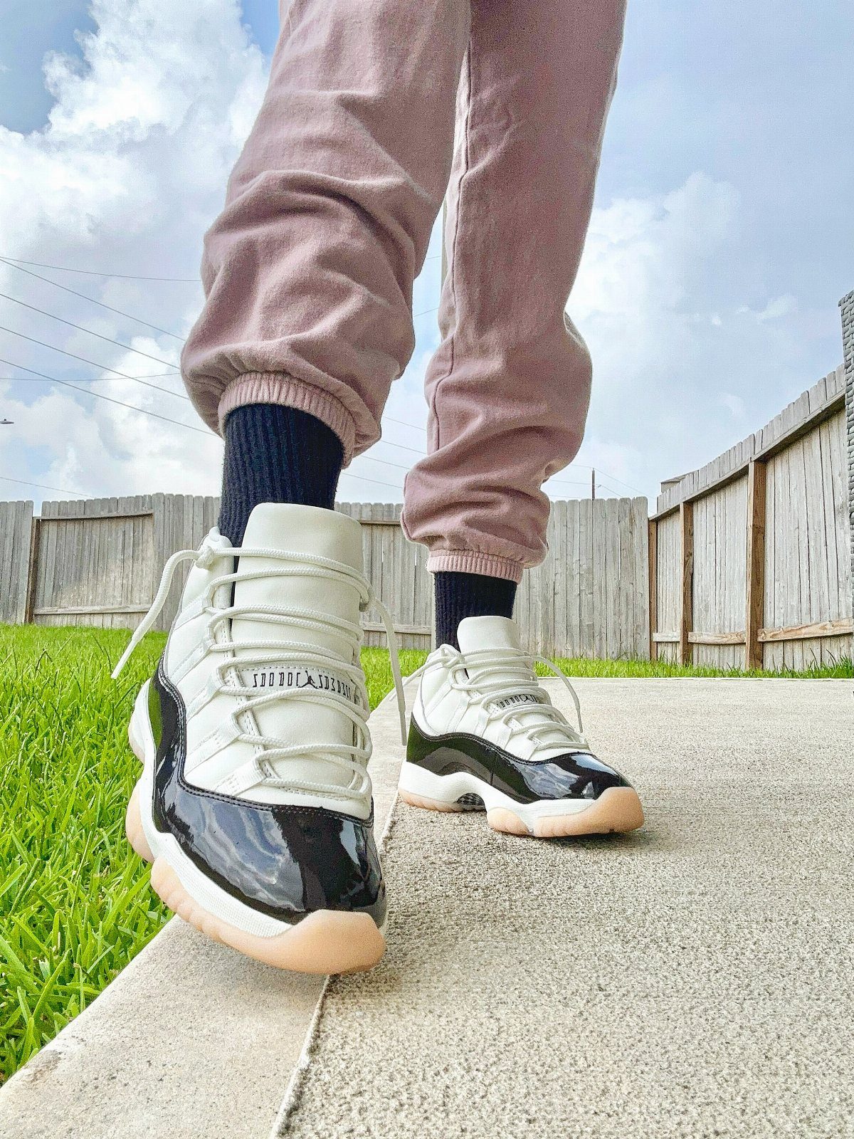 White and black patent leather Jordan sneakers worn with mauve joggers and black socks.