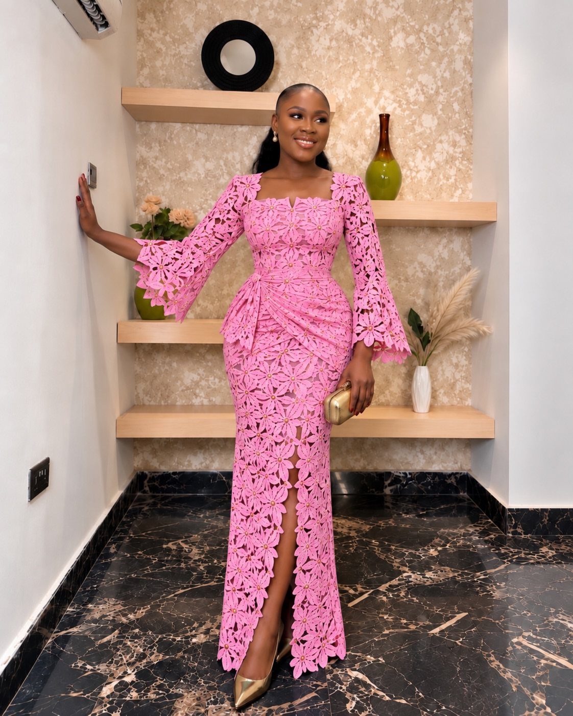 Woman in a long pink floral lace dress with bell sleeves and front slit