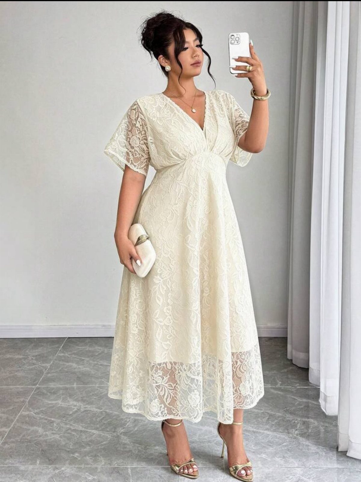 Woman in cream lace midi dress with V-neck and gold strappy heels.