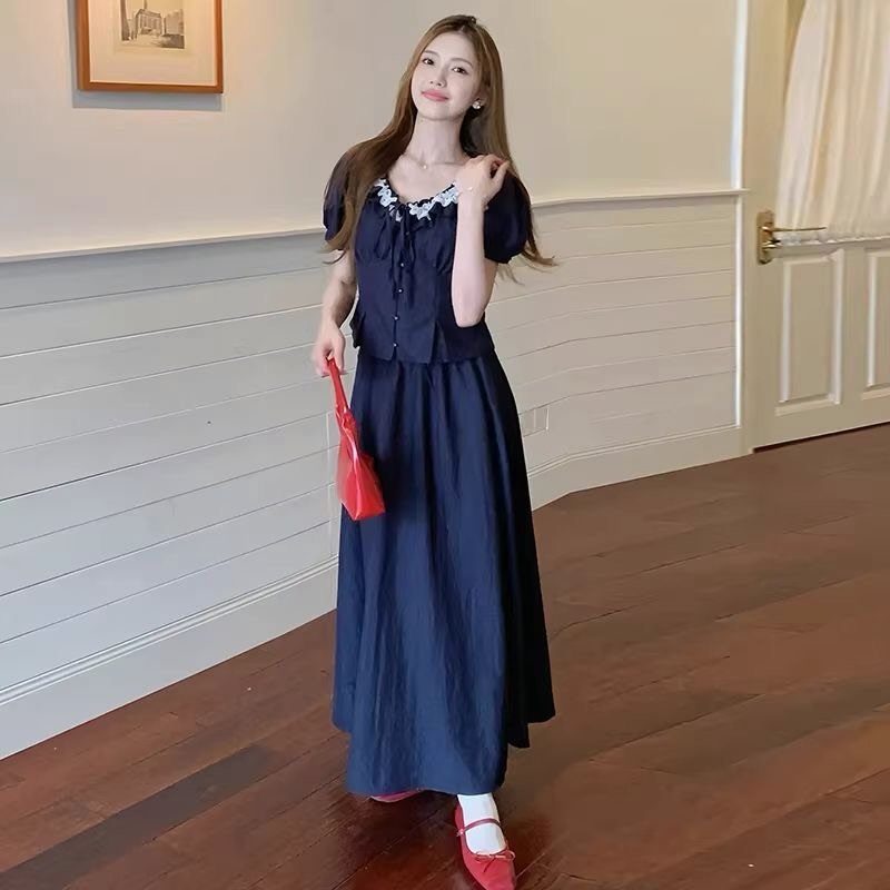 Woman in navy blue midi dress with white lace trim and red accessories.