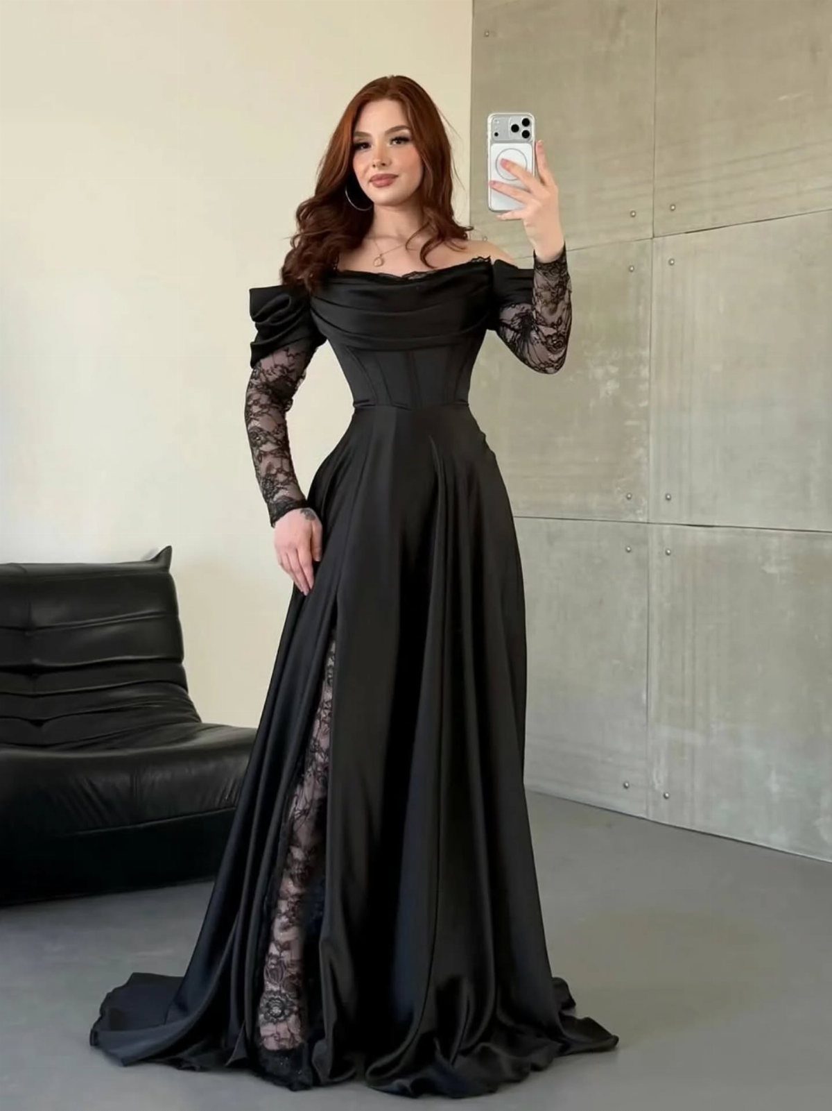 Woman in black off-the-shoulder gown with lace sleeves and a high leg slit.