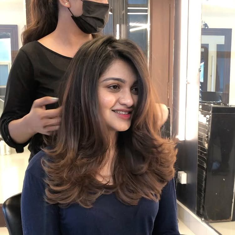 Woman with voluminous brown layered blowout hair smiling in a hair salon
