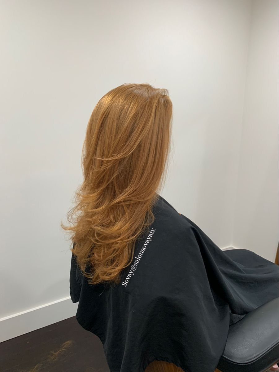 Long strawberry-blonde hair with voluminous layers and curled ends in a salon setting.