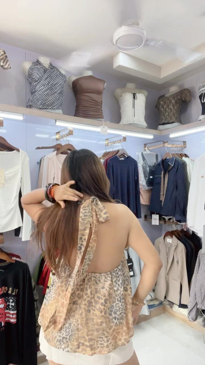 Woman wearing a leopard print halter top and white shorts in a clothing store.