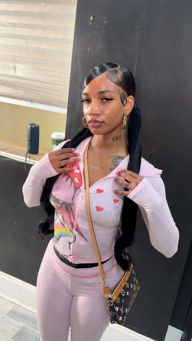 9 Long African Hair Ideas for Braids, Curls and Waves 9 Woman with long black hair in ponytails wearing a pink graphic outfit.