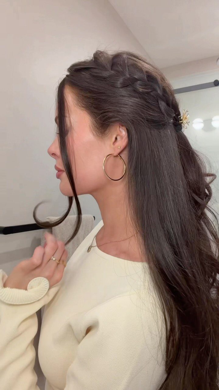 Woman with long dark hair in a braided half-up hairstyle with gold clip