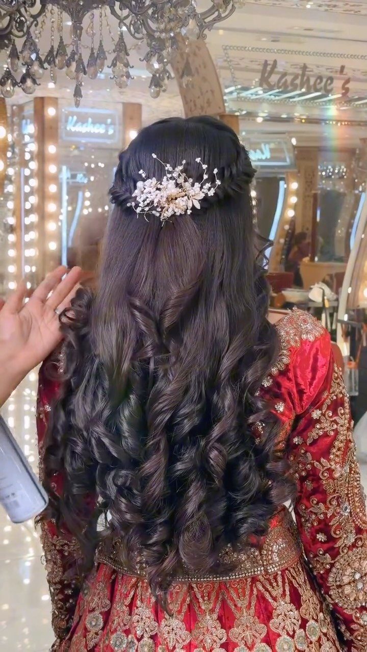 Long curly brown hair in a half-up hairstyle with a white floral accessory