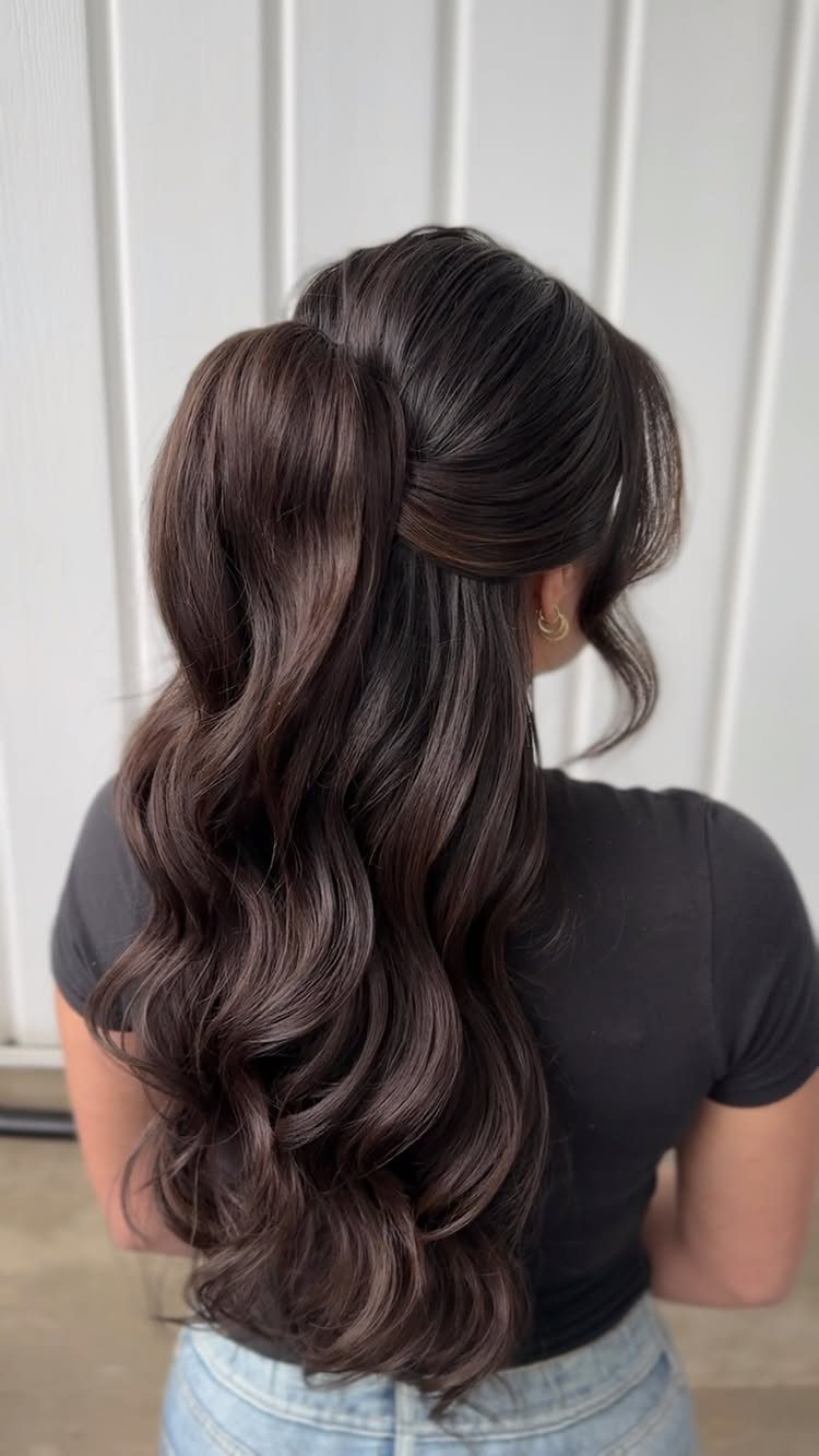Long wavy brown hair styled in a voluminous half-up ponytail from behind.