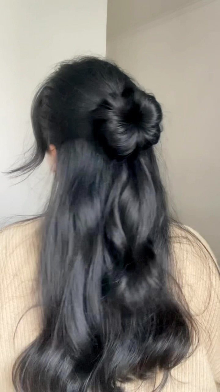 Long wavy black hair styled in a half-up rosette bun from behind.
