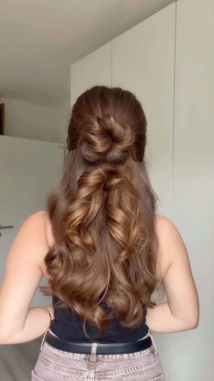 Woman with long wavy brown hair in a half-up knotted bun hairstyle.