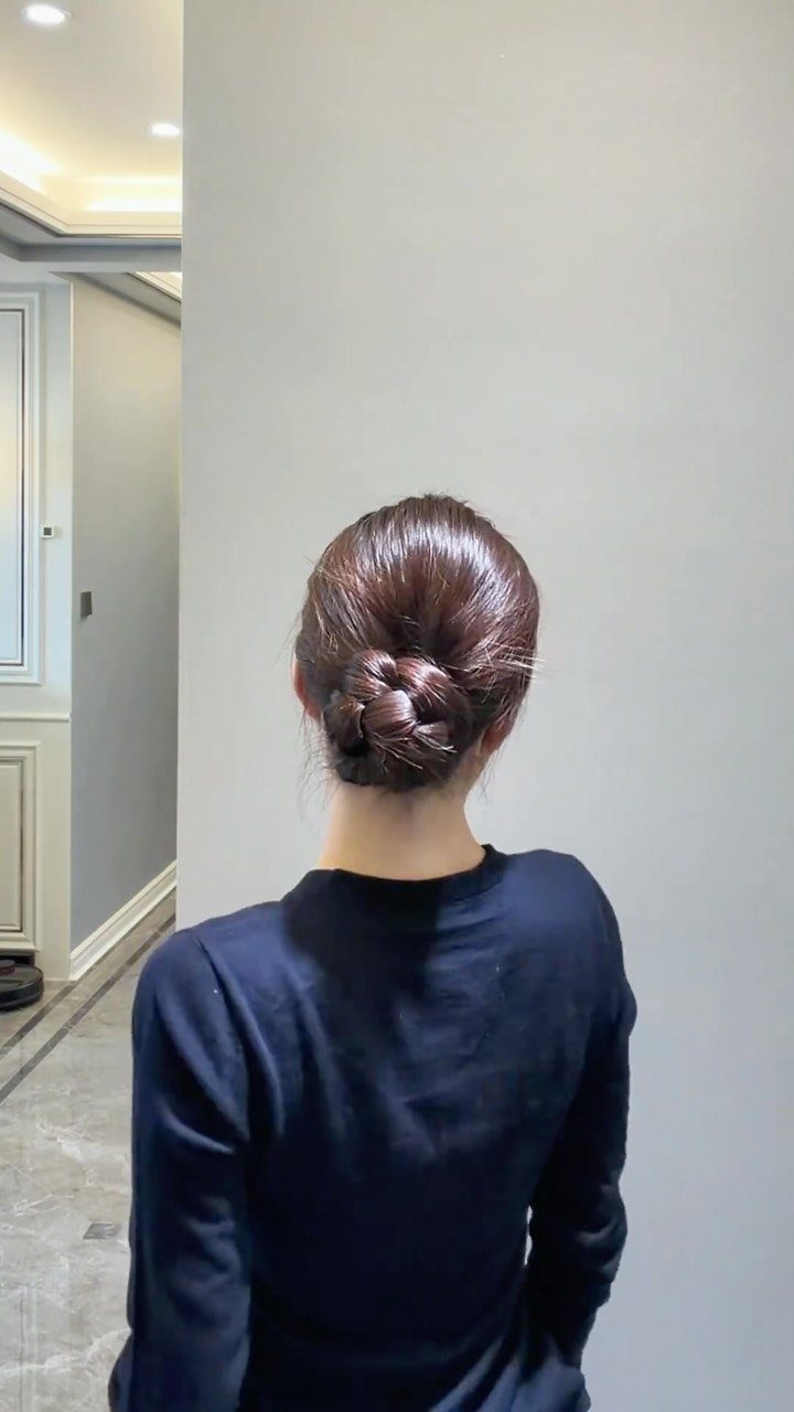 9 Long Hair Tutorial Ideas: Braids, Buns and Ponytails 7 Braided bun hairstyle on reddish-brown hair, viewed from the back against a wall.