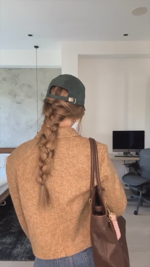 9 Long Hair Tutorial Ideas: Braids, Buns and Ponytails 9 Woman from behind with a long brown braid, wearing a green cap and blazer.