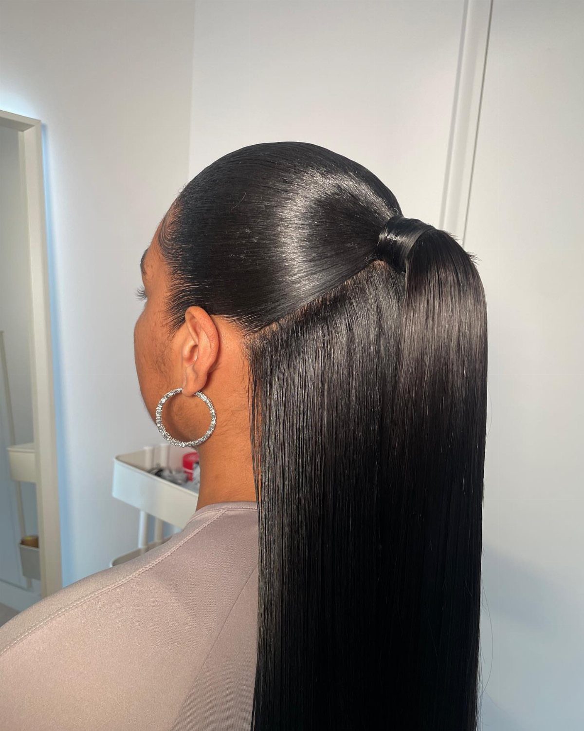 9 Long Hair Tutorial Ideas: Braids, Buns and Ponytails 8 Slicked back ponytail on a person with long straight black hair and hoop earrings.