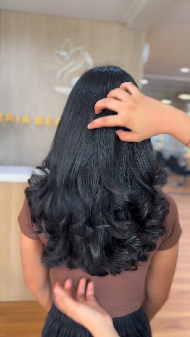 9 Medium Length Perm Hair Ideas with Waves and Curls 7 Medium length dark black hair with voluminous curls at the ends in a salon