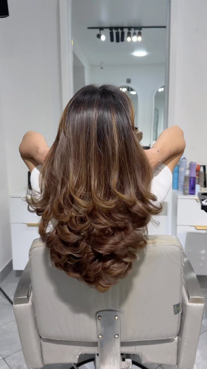 9 Medium Length Perm Hair Ideas with Waves and Curls 8 Medium length brown hair with voluminous curly perms seen from behind in salon