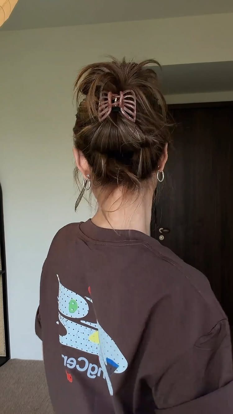 Brown hair styled in a messy high bun secured with a claw clip.