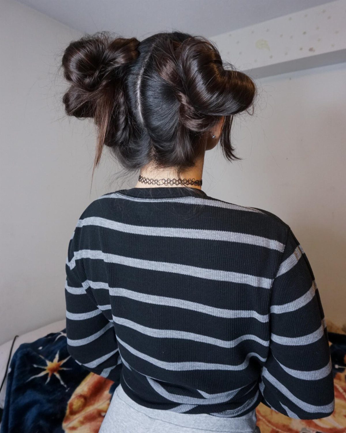 Person with dark hair styled in two messy buns wearing striped shirt