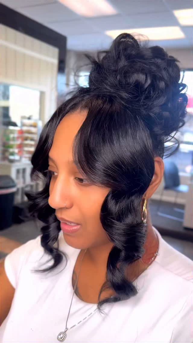 Woman with dark curly hair styled in a high voluminous messy bun.